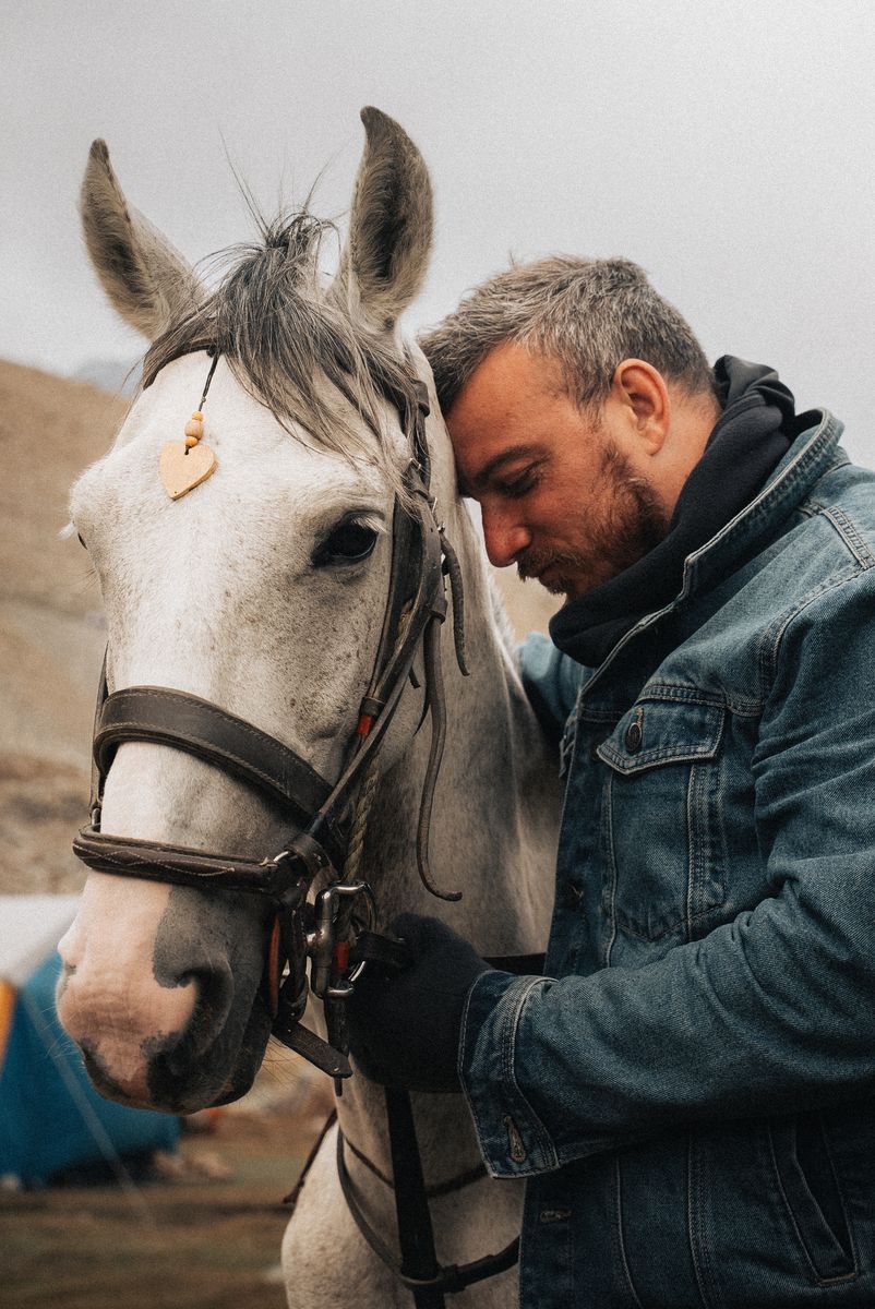 Sami Hermes resting his forehead against a white horse at camp